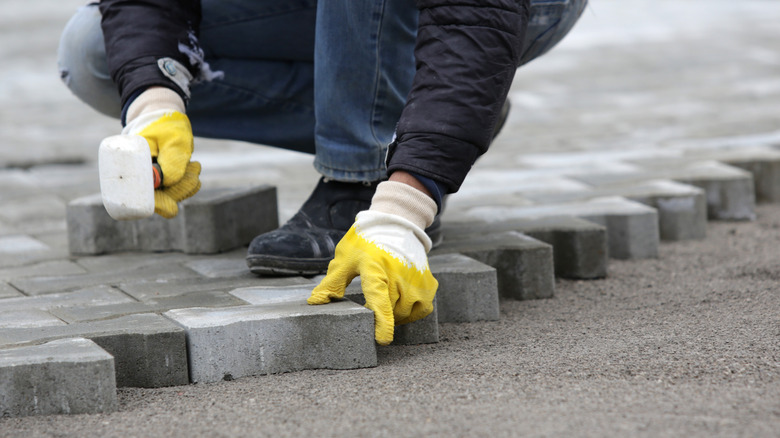 A person laying patio paving stones