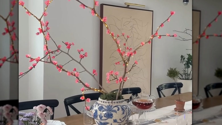 A gorgeous vase holding pink flowers on a branch