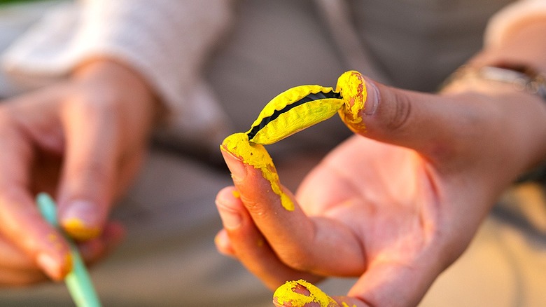Close-up of a person holding a bottle cap painted yellow