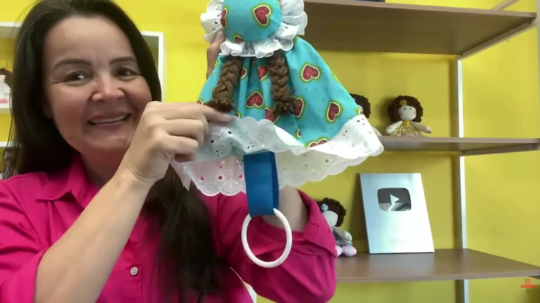 Woman holding up a towel holder shaped like an old-fashioned doll