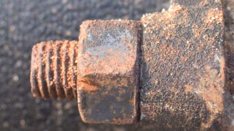 A close-up of a dirty and rusty bolt