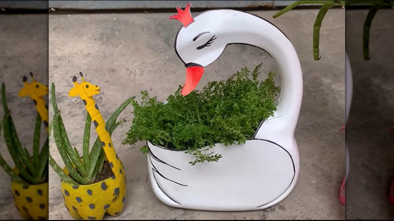 A white DIY swan planter holding a small plant