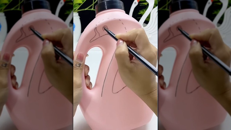 Person drawing a swan on a detergent container