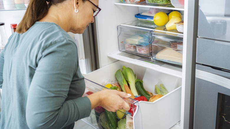 Woman looking into her full fridge drawers