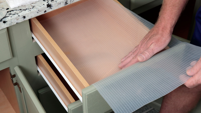 Man applying a shelf liner to the inside of a kitchen drawer