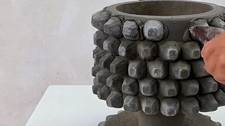 Person applying cement paste to a DIY cement planter pot.