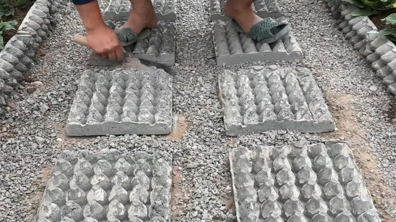 Pavers shaped like egg cartons being laid on soil
