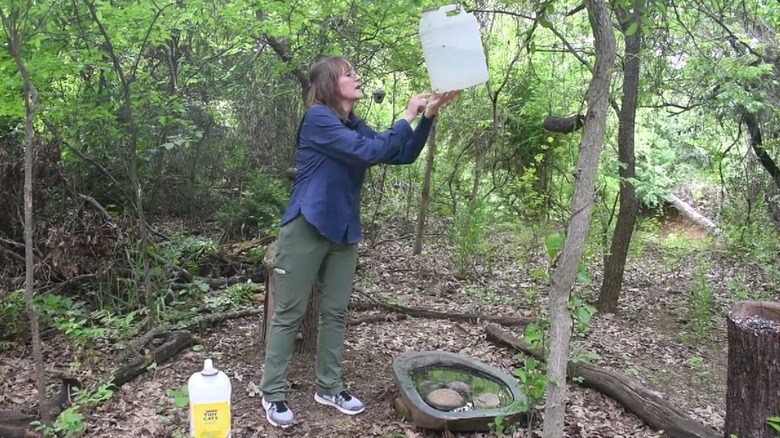 woman showing how a cat litter jug can create a drip bird bath