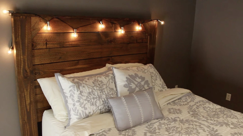 A wooden headboard made from horizontal fence boards styled with a string of lights
