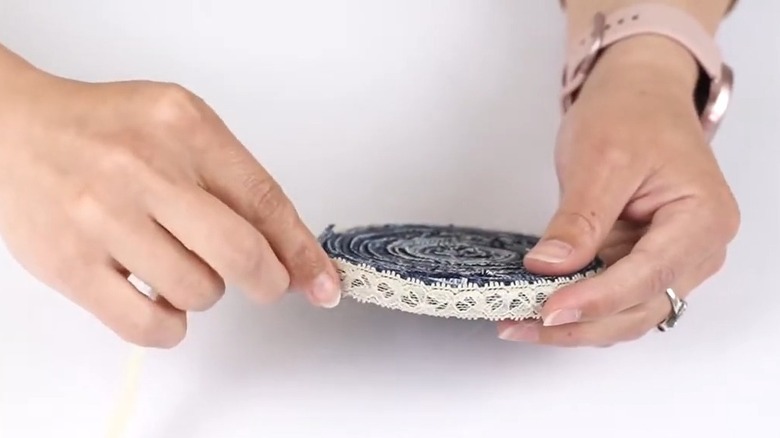 Female hands attaching a lace border to a jeans coaster