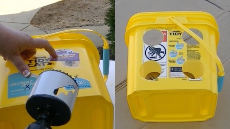A person uses a hole-making drill bit to drill large holes in the sides of a large yellow kitty litter bucket.