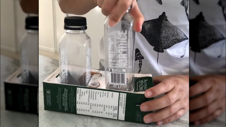 Hands inserting small plastic bottles in a milk carton holder