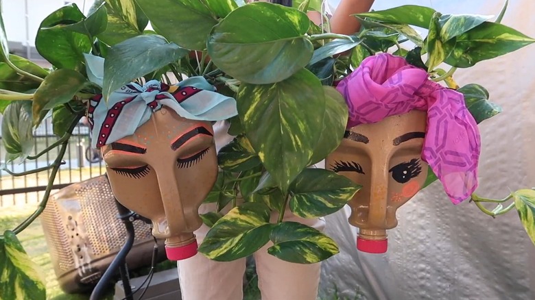 A milk jug face planter being held in a backyard.