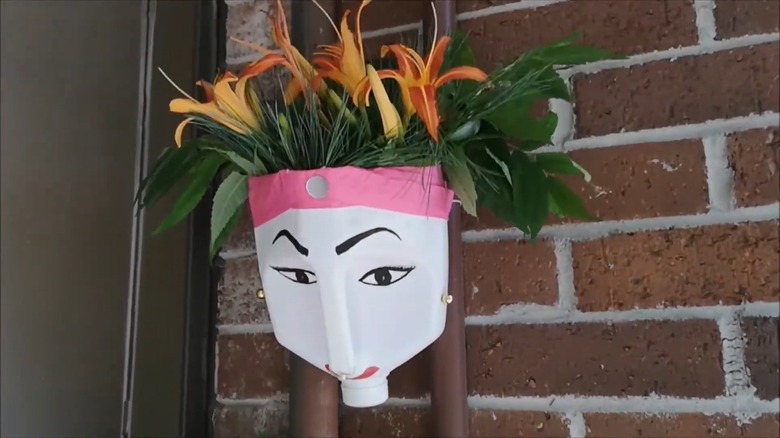 A milk jug painted like a face and repurposed as a planter.
