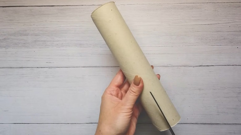 Hand cutting an empty towel tube with scissors