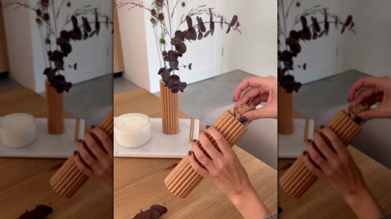 A hand putting crumpled paper towel in a fluted vase