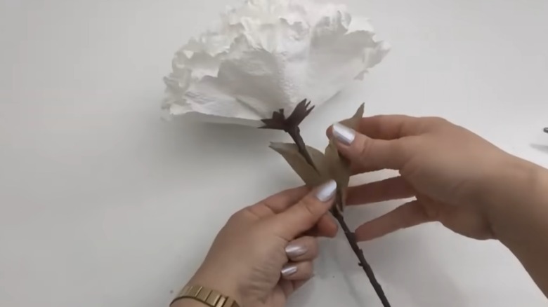 person adhering DIY leaves to DIY paper towel flower