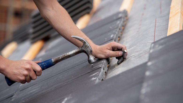 A person installing roof tiles on a house