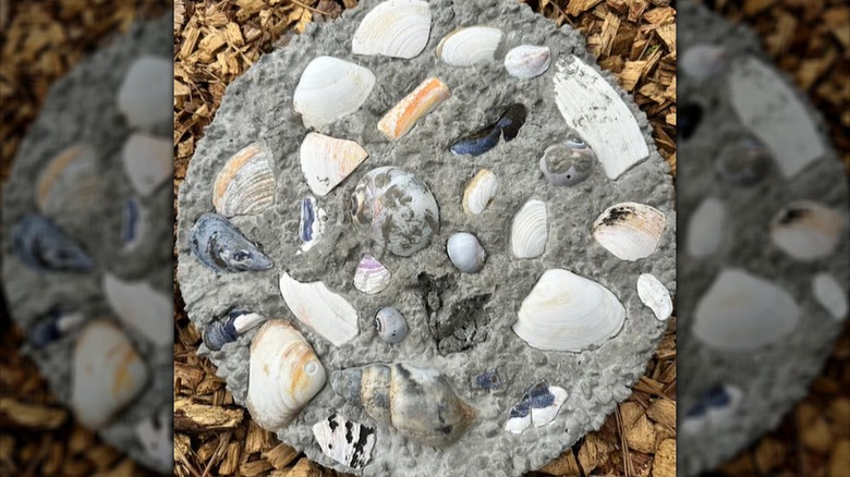 A round paving stone is decorated with various seashells.
