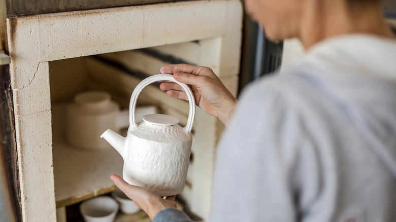 Person grabbing teapot from shelf