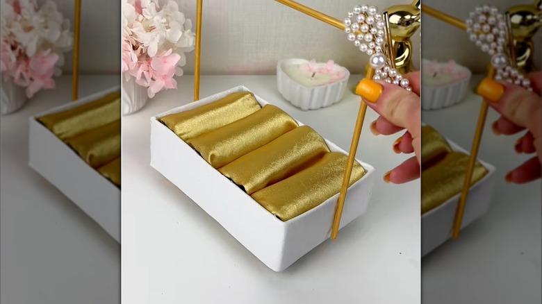 A gold DIY jewelry box made from toilet paper tubes.