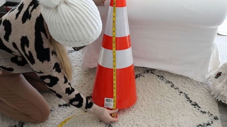 A woman measuring a traffic cone for a DIY.
