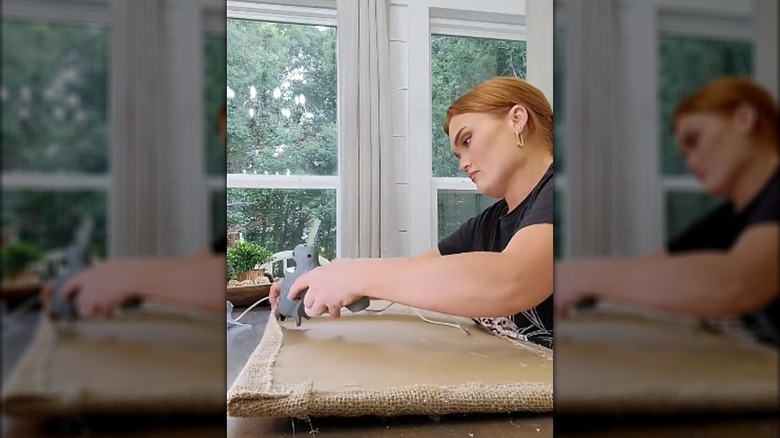 Demonstrator gluing burlap to a frame design