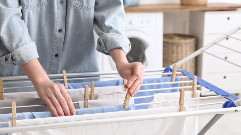 Someone placing wooden clothespins on a drying line