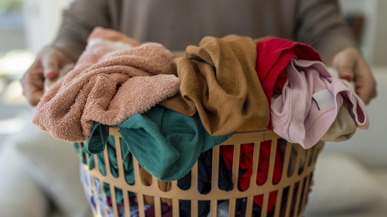 A person carrying a laundry basket full of colorful clothes