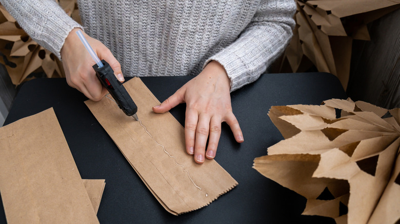 Woman adding hot glue to brown paper bags