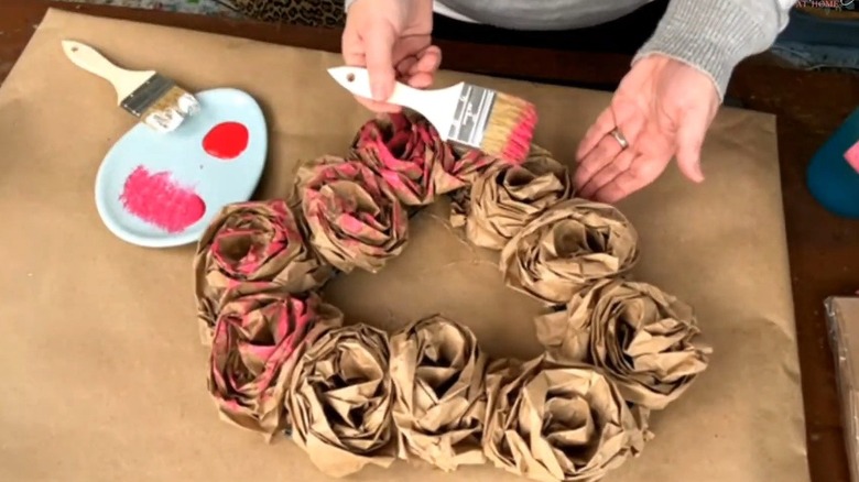 Woman painting brown paper bag roses red