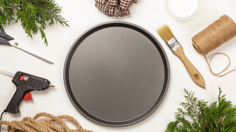 A pizza pan and other craft supplies and tools on a white tabletop.