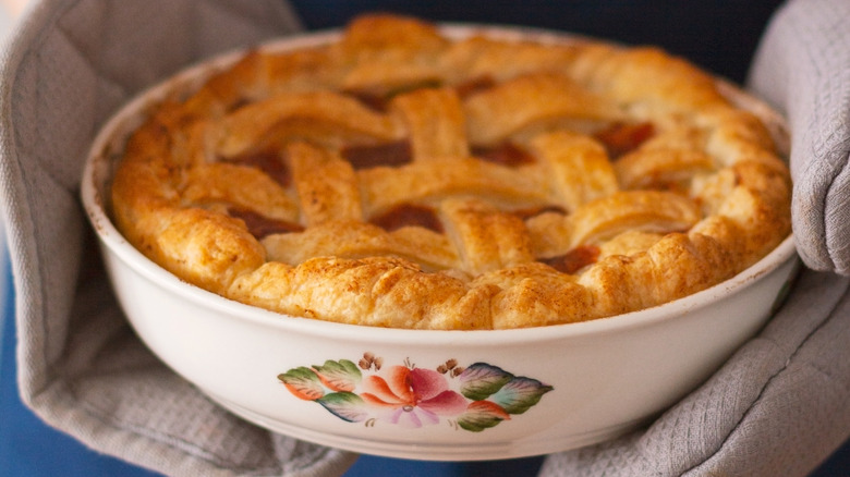 person holding a pie dish with two pot holders