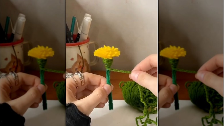 A person wraps yarn around the pipe cleaner stem of a faux dandelion.