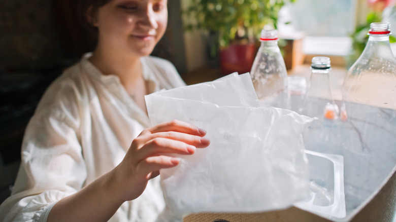 Woman holds up a plastic bag.
