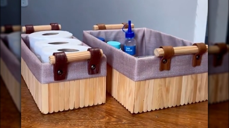 Cardboard storage box covered with fabric and popsicle sticks.