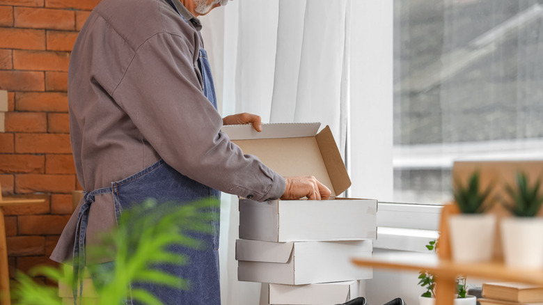Man opening top box of stacked shoe boxes.