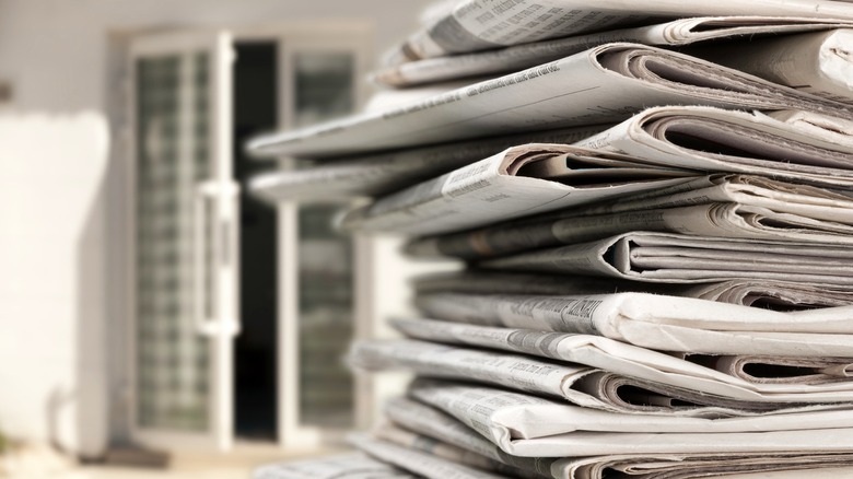 Stack of newspapers outside with open back door in background