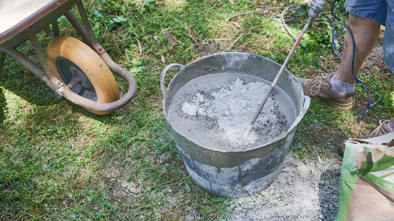A person mixing concrete next to a wheelbarrow