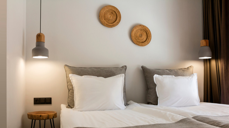 Straw wicker plates as wall art on white wall behind bed