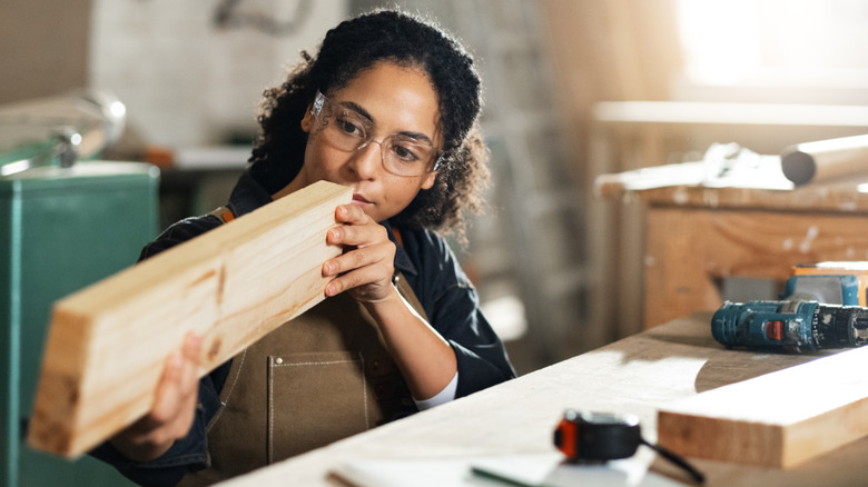 Woman examining wood board in workshop