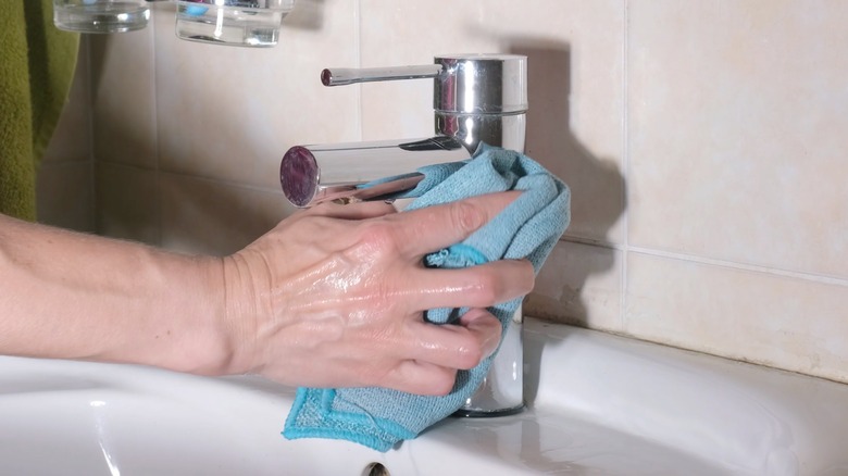Wiping down chrome faucet with blue cloth