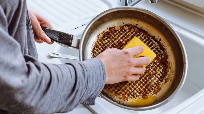 Someone cleaning a greasy pan