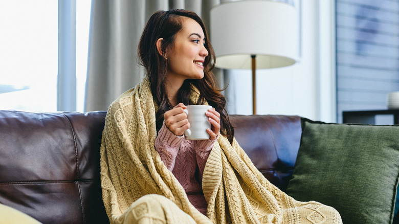Woman drinks coffee with throw blanket