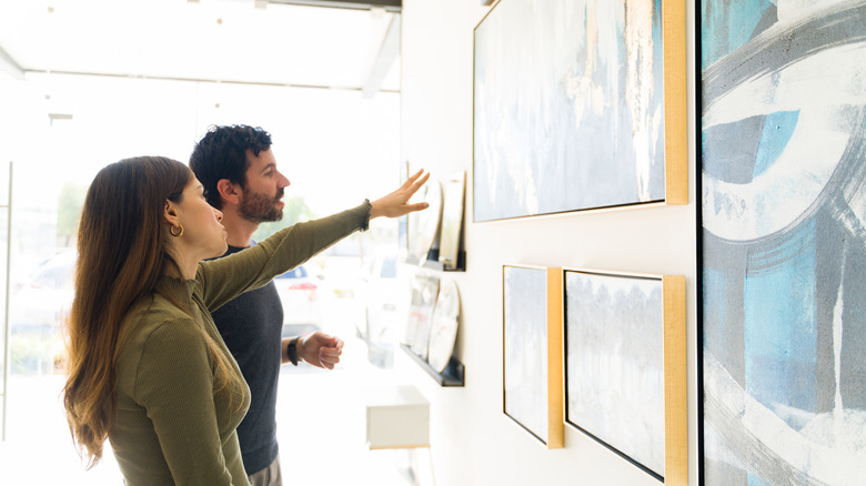 A young couple looking at wall art pieces in a store.