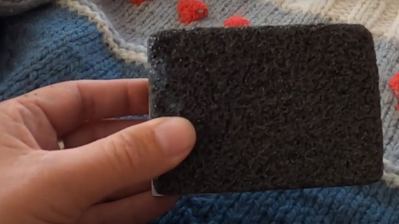Hand holding sweater pumice stone