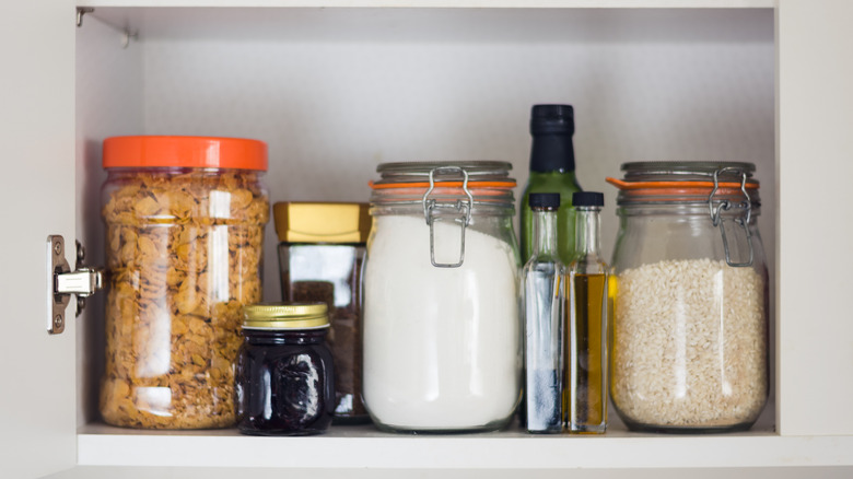 Glass jars of food line shelves in a clean pantry.