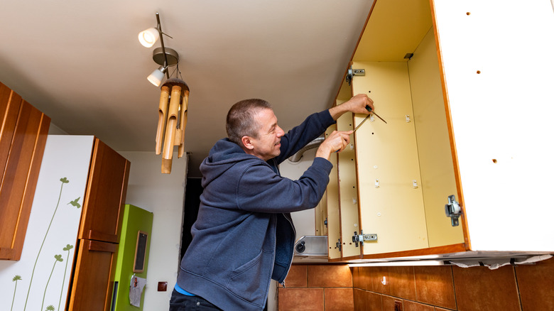 man removes cabinet components