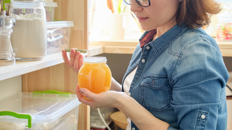 person holding honey jar in pantry
