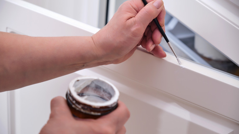 Person painting cabinet door white
